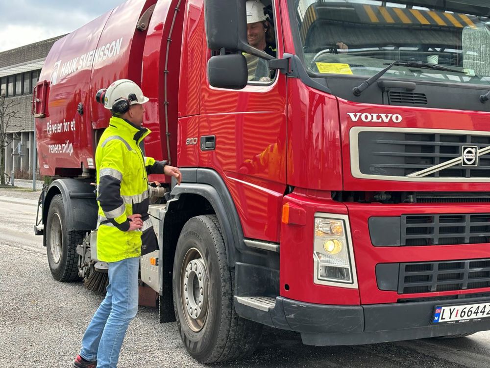 stort rødt kjøretøy, mann står på utsiden av bilen og snakker med sjåfør som har rullet ned vindet, Industripark.