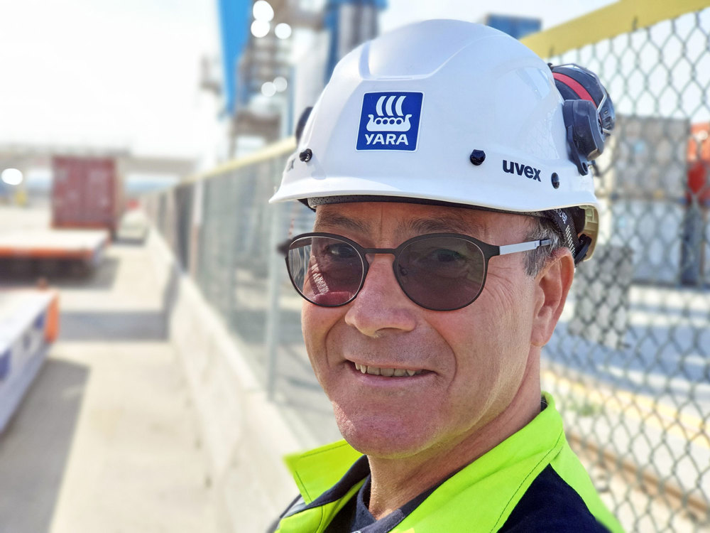 man with dark glasses and white helmet standing in logistic area