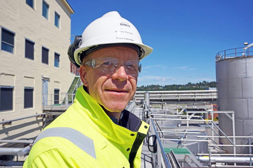 portrett av mann i hvit hjelm og gul jakke, poserer, står ute,