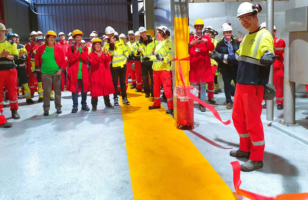 a man has just cut the ribbon and cheering crowds in background are clapping their hands