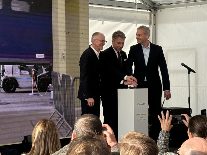 tre menn på scenen, alle tre med hver sin hånd på den store røde knappen