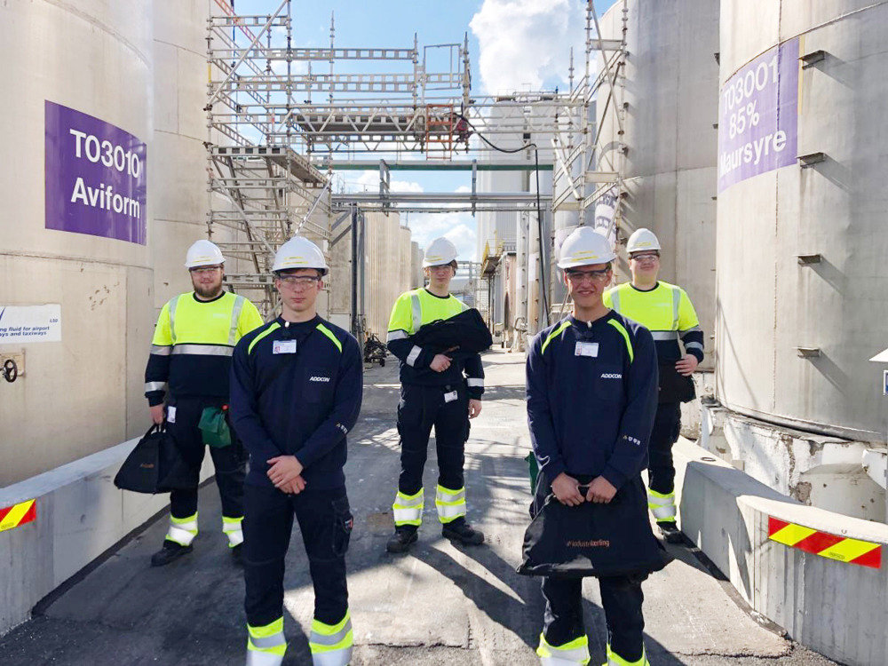 five apprentices, posing, standing between two tanks