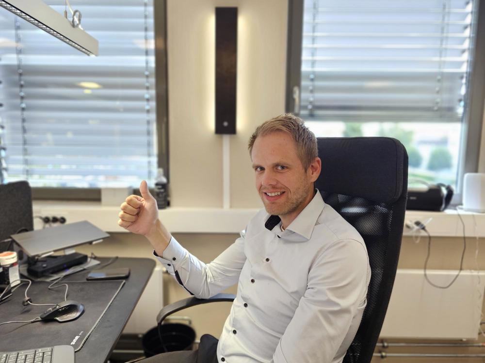 man sitting in office chair, thumbs up, smiling, posing