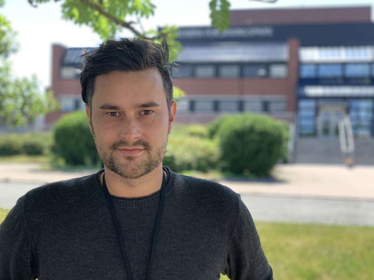 portrait of young man, posing, in front of red brick building, large entrance, steps