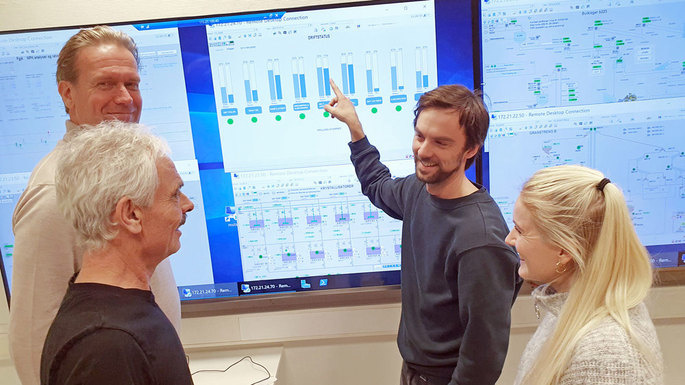 four people standing in front of monitor, process data