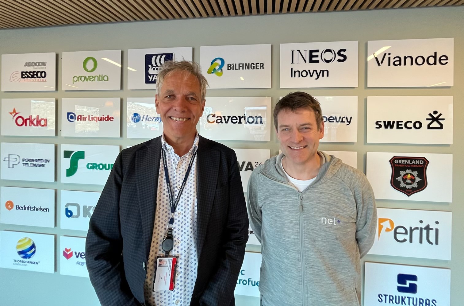 two men in front of a wall with logoes