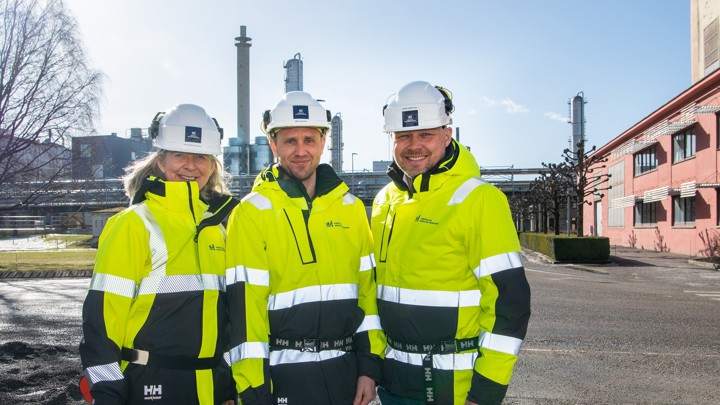 three persons, posing, helmet and yellow jackets, industrial park, winter