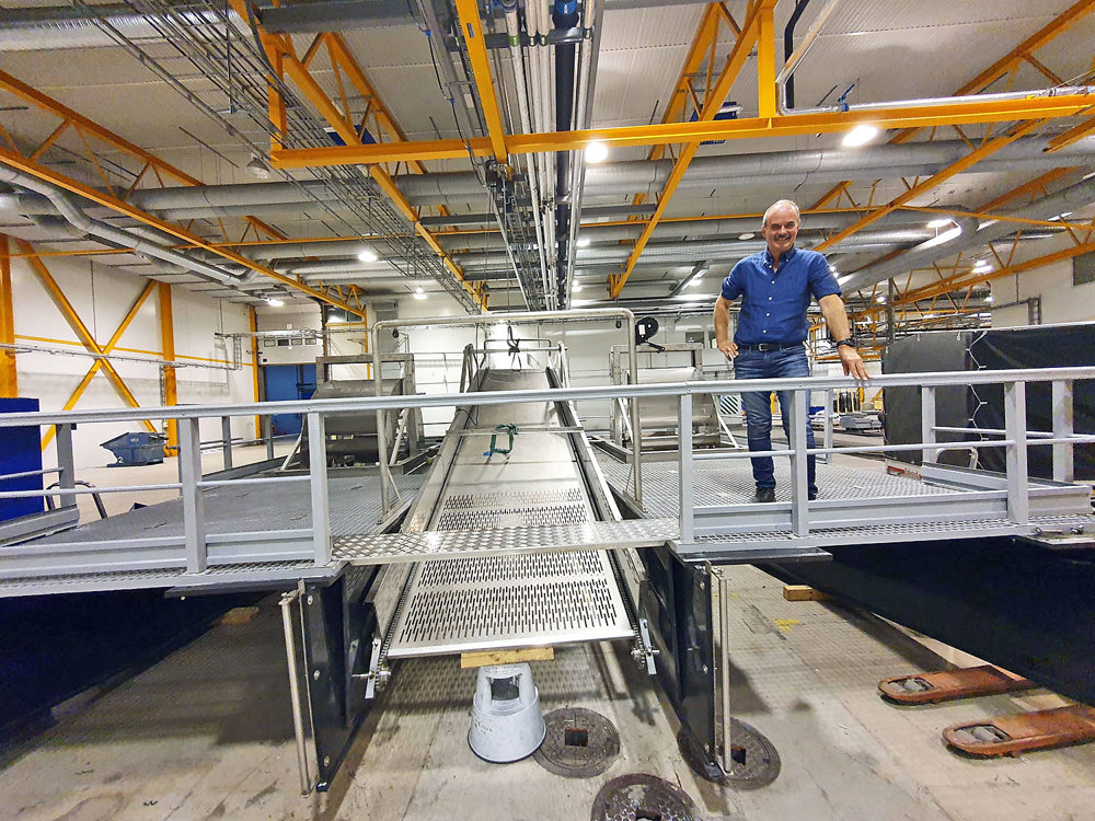 man standing in ha big hall on a platform of machine gathering plastic waste