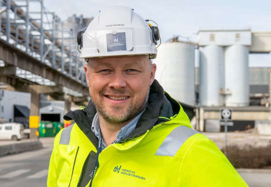 man, portrait, posing, beard, white helmet, yellow jacket, industry in background