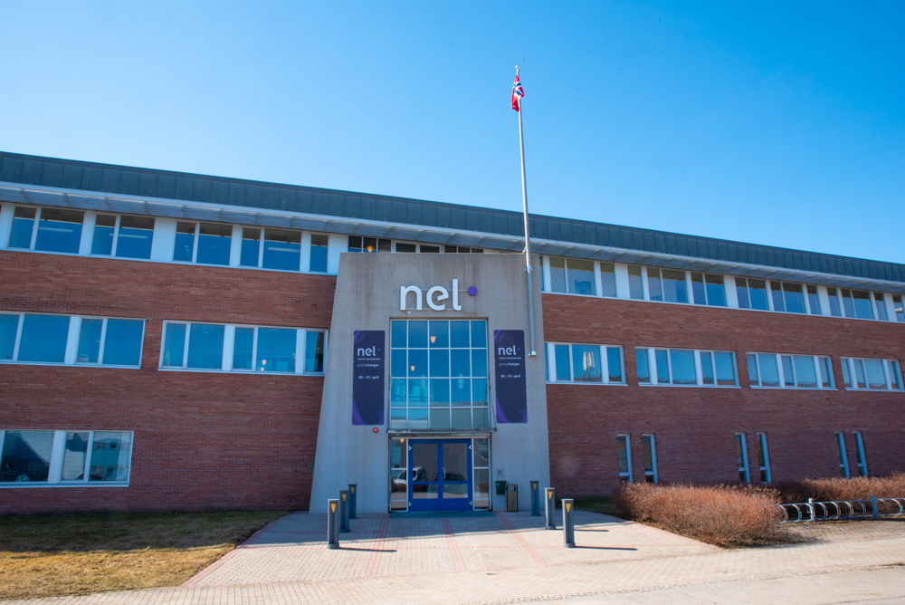 red brick building with windows and a flagpole outside