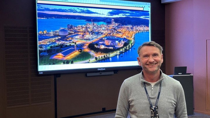 mann, poserer, står foran stor skjerm i møtelokale