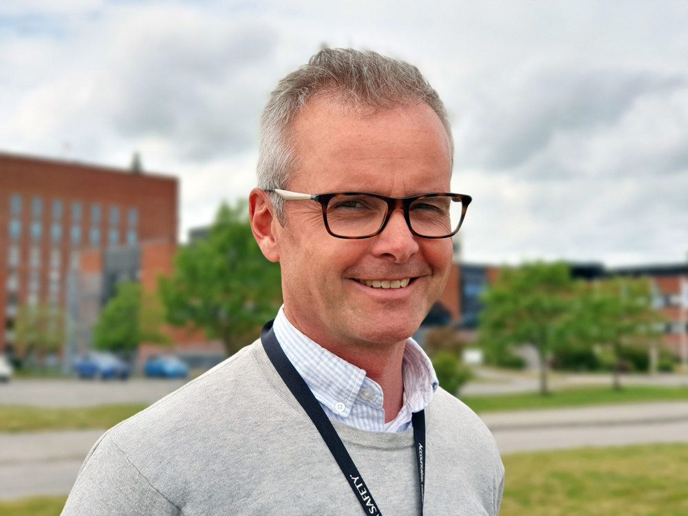 man with glasses, green grass and trees in background