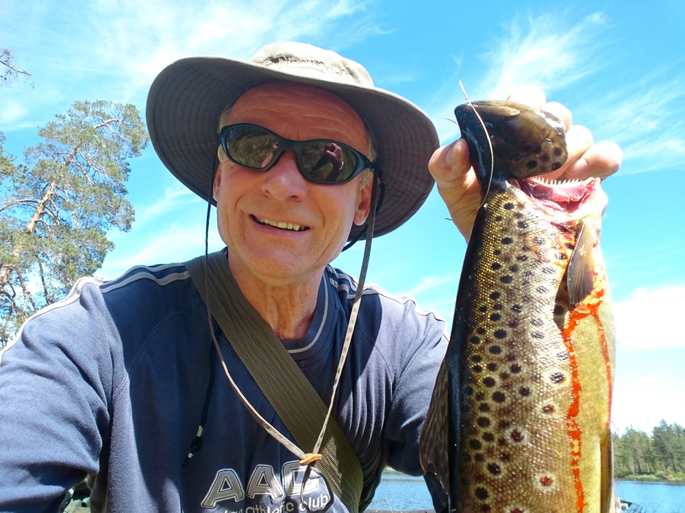 man with sunglasses and hat, displaying a great catch of fish, smiling
