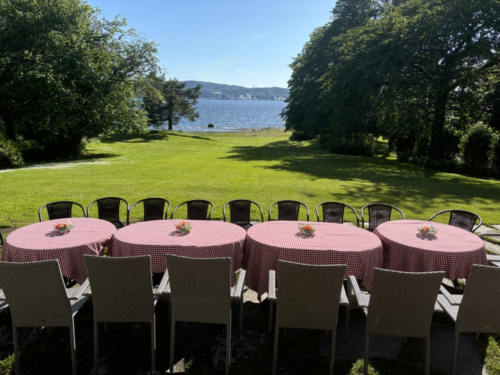 big garden, round tables in front, great view to sea, big trees and blue sky