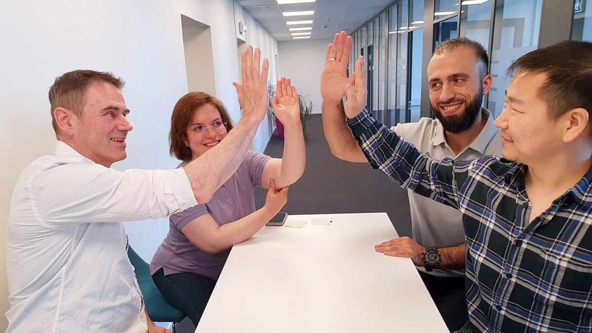 fire personer ved et bord, high five, kontorlokale