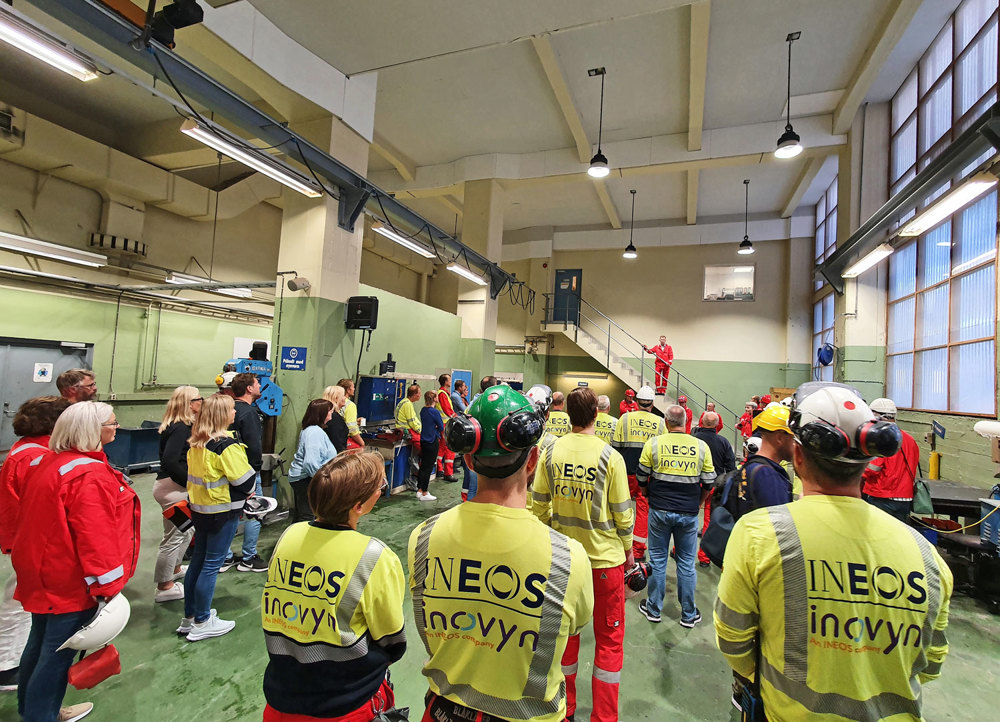 crowd of employees standing in industrial hall listening to their manager on the stairs