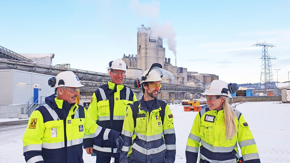 fire personer ute i industripark, arbeidsantrekk, verneutstyr, vinter