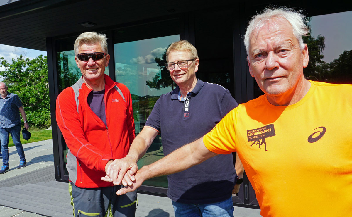 three men, posing, holding out one arm each, hands on top of eachother.