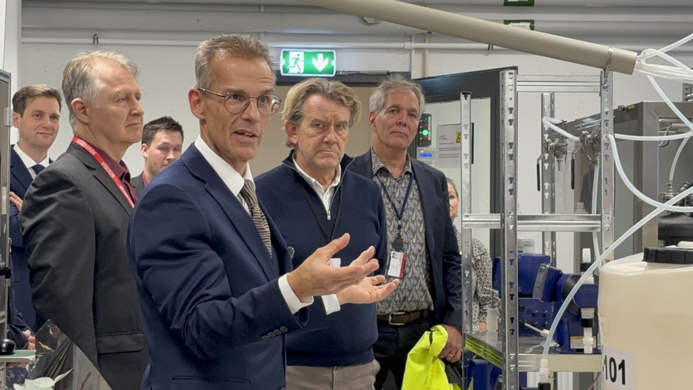 man in suit talks to guests standing near in the pilot facility