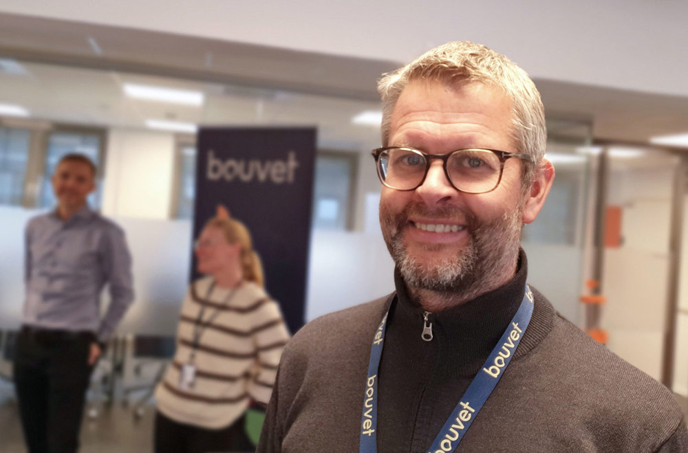 man wearing brown jumper standing in an office area