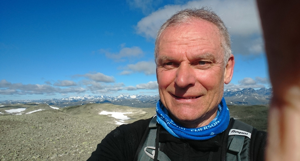 selfie, man with short grey hair hiking in the mountains.