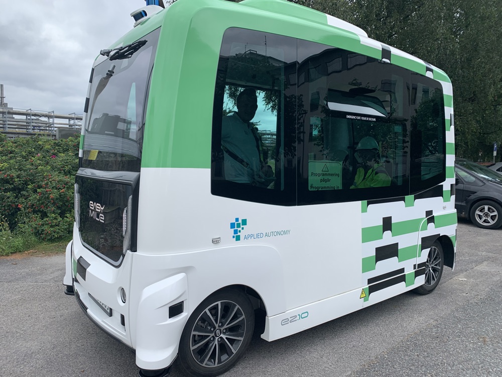 liten minibuss, hvit og grønn, står parkert langs vei i industripark
